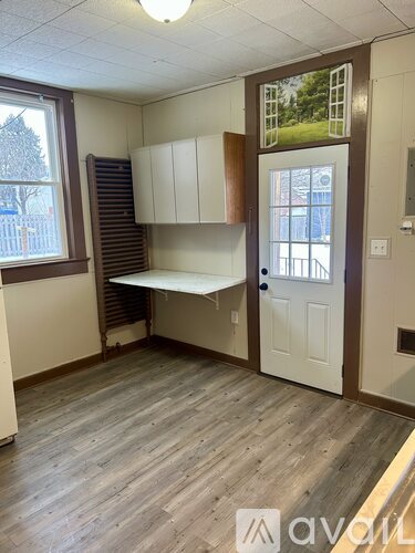 A room with a window, wooden floors, and a white door.