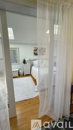 A bedroom with a bed covered in white bedding and a white canopy.