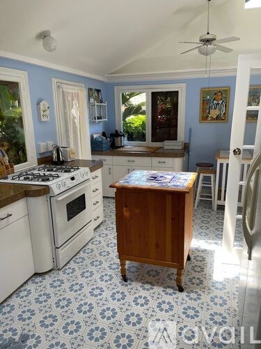 A kitchen with a white stove top oven and white cabinets.