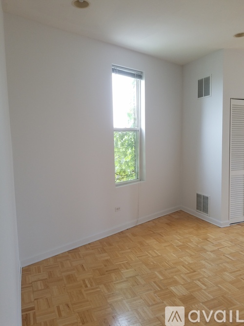 A room with a window and a wooden floor.