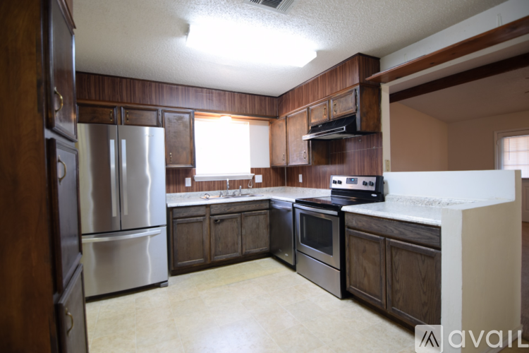 A kitchen with wooden cabinets and a stainless steel refrigerator.