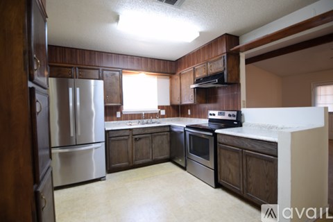 A kitchen with wooden cabinets and a stainless steel refrigerator.