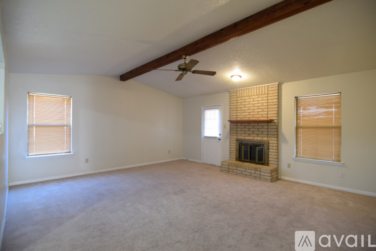 A spacious living room with a fireplace and a ceiling fan.