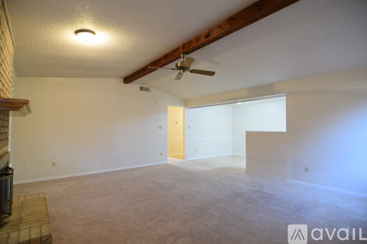A spacious room with a ceiling fan and a fireplace on the left side.