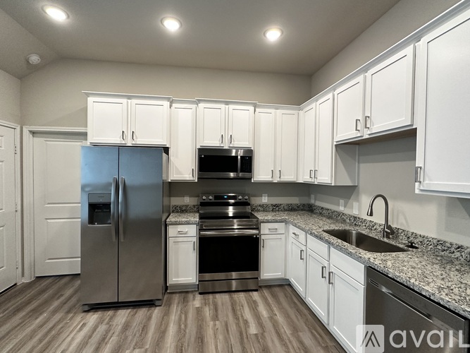 A kitchen with white cabinets and a stainless steel refrigerator.