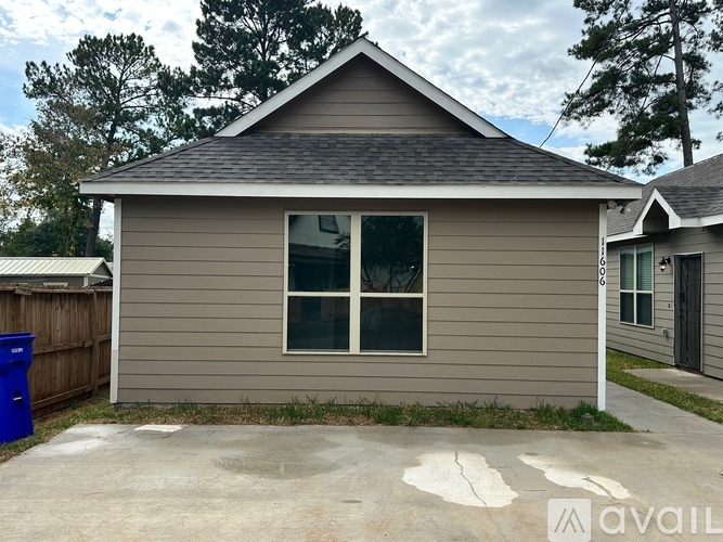 A small house with a grey siding and a black roof.