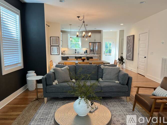 A living room with a grey couch and a coffee table with a vase on it.