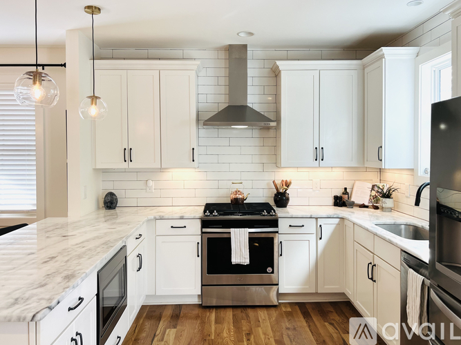 A modern kitchen with white cabinets and a marble countertop.