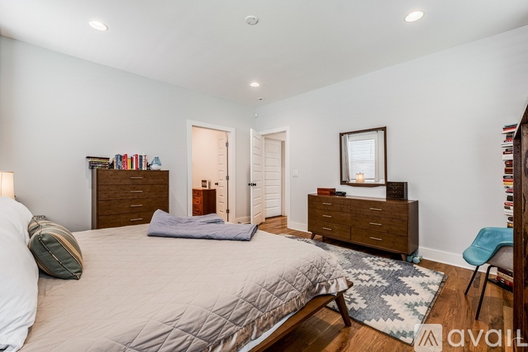 A bedroom with a large bed, a chair, and a bookshelf.