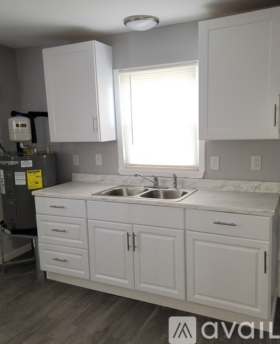 A kitchen with white cabinets and a marble countertop.