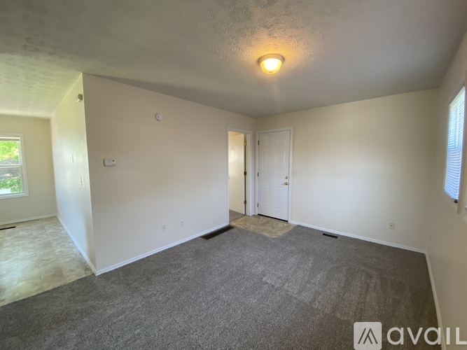 A room with a carpeted floor and a door is available for rent.