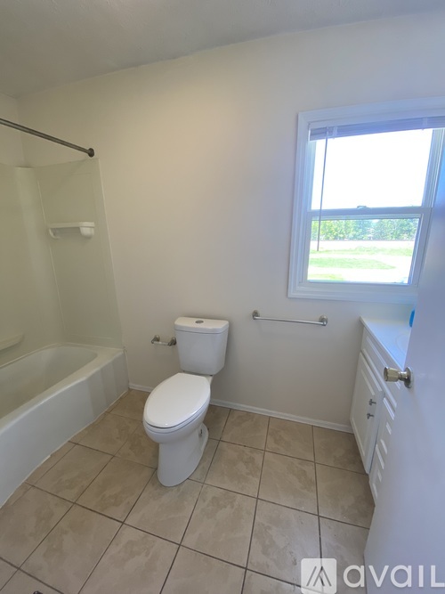 A white toilet in a bathroom with a window.