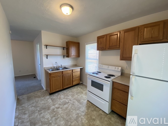 A kitchen with white appliances and wooden cabinets.