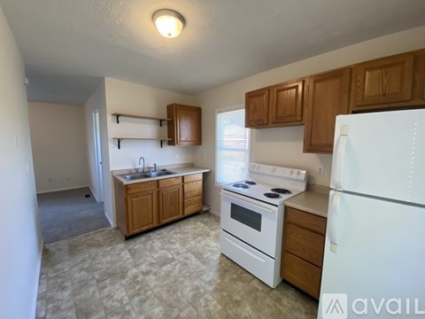 A kitchen with white appliances and wooden cabinets.