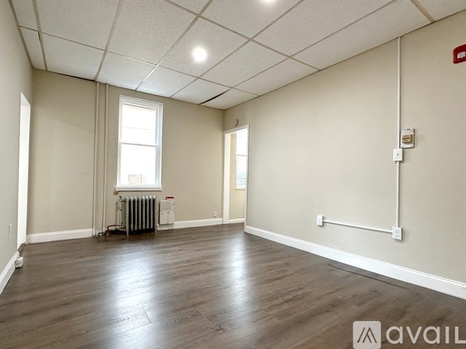 A spacious room with wooden flooring and white walls.