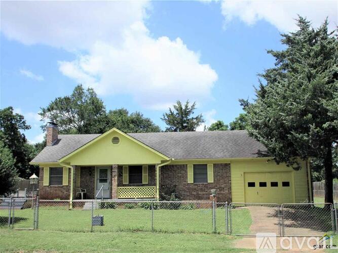 A yellow house with a grey roof and a fence in front of it.