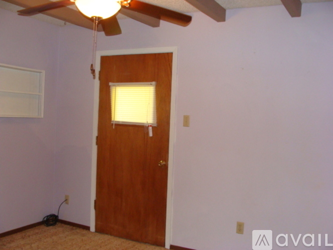 A room with a wooden door and a ceiling fan.