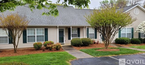 A house with a green lawn and trees in front.