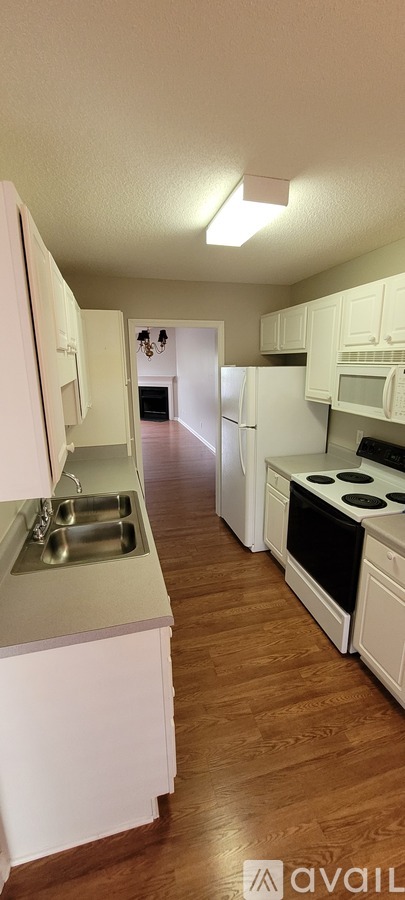 A kitchen with white cabinets and a wooden floor.