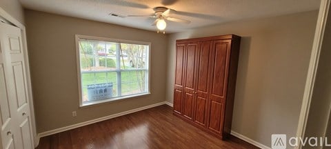 A room with a window and a wooden wardrobe.