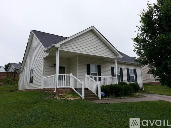 A house with a porch and a tree in front.