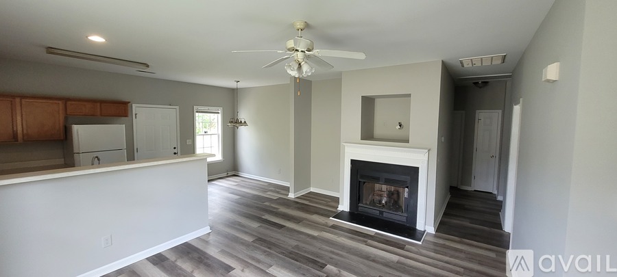 A living room with a fireplace and a kitchen area in the background.
