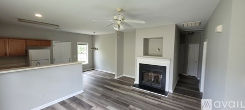 A living room with a fireplace and a kitchen area in the background.