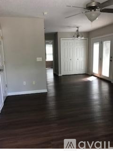 A room with a ceiling fan and wooden flooring.