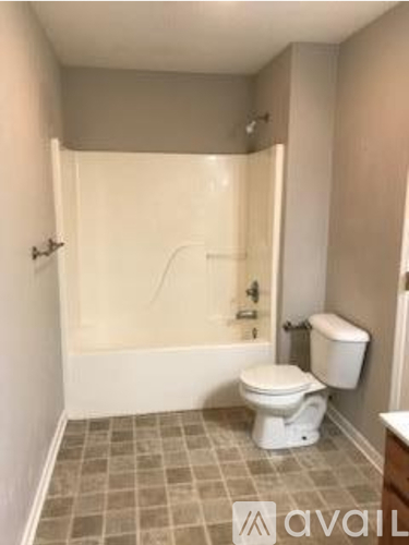 A bathroom with a toilet, tub, and tile floor.