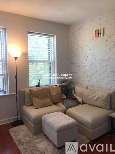 A living room with a white couch and a white brick wall.