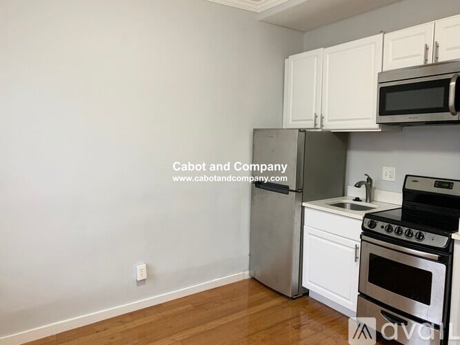 A kitchen with white cabinets and a stainless steel refrigerator.