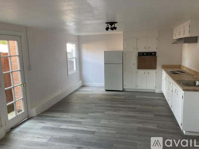 A kitchen with white cabinets and a grey floor.
