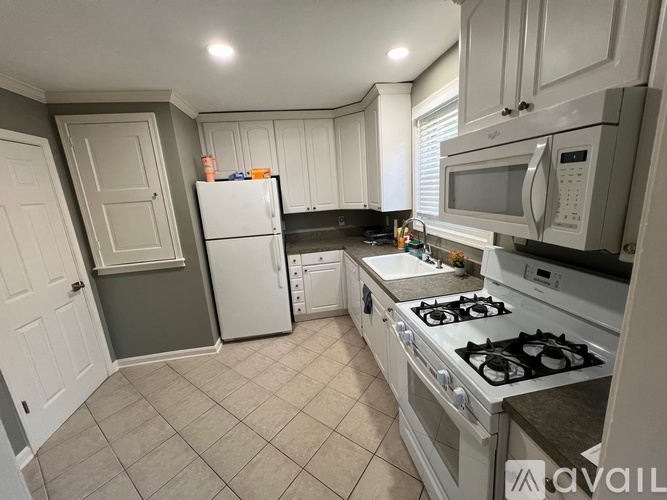 A kitchen with white cabinets and a white fridge.