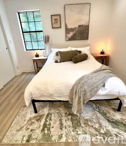 A bedroom with a large bed and a painting on the wall.
