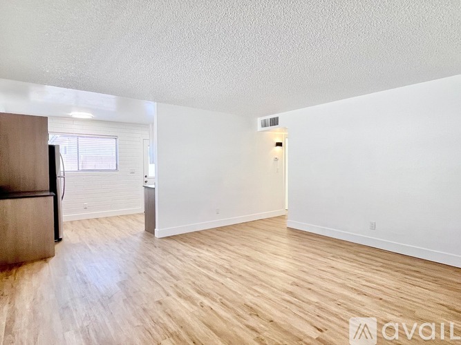 A spacious room with wooden flooring and white walls.