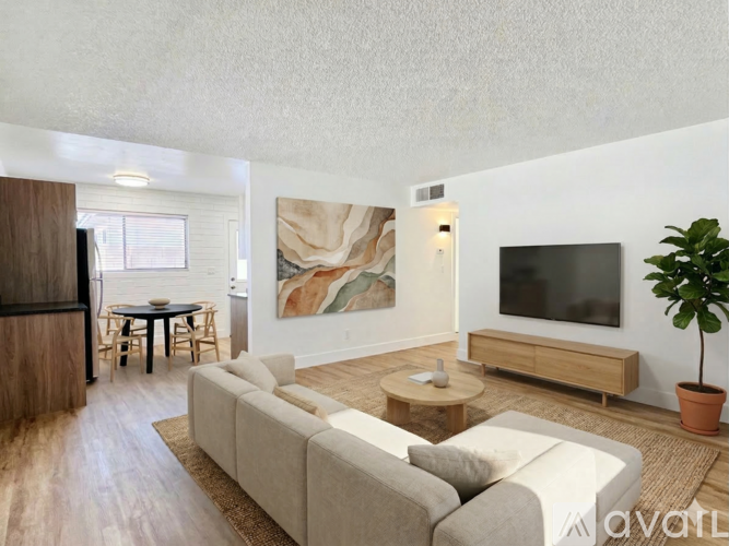 A living room with a couch, a coffee table, a TV, and a potted plant.