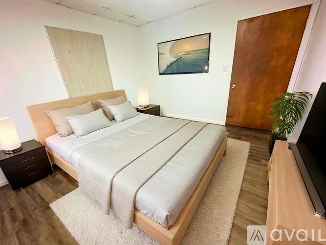 A bedroom with a large bed, a lamp, and a painting on the wall.