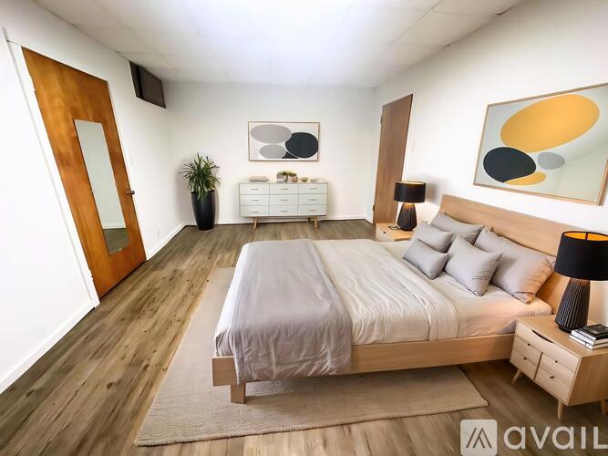 A bedroom with a bed, nightstand, and a plant.