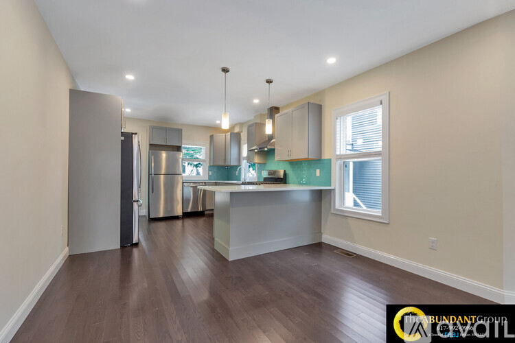 A kitchen with a refrigerator, stove, and cabinets.