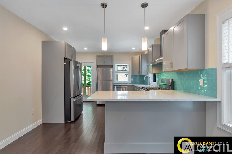A kitchen with a refrigerator, cabinets, and a counter.