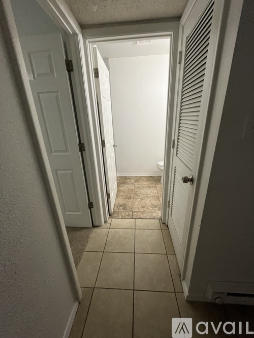 A hallway with white doors and tiled floors.