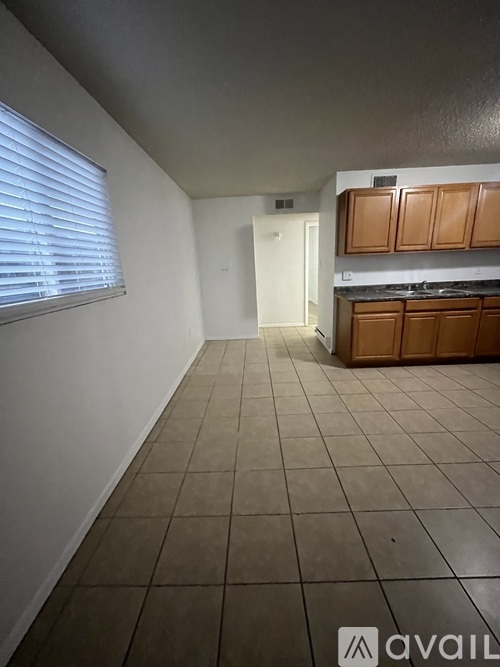 A kitchen area with brown cabinets and a tiled floor.