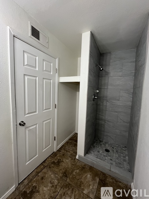 A bathroom with a white door and a shower with tiled walls.