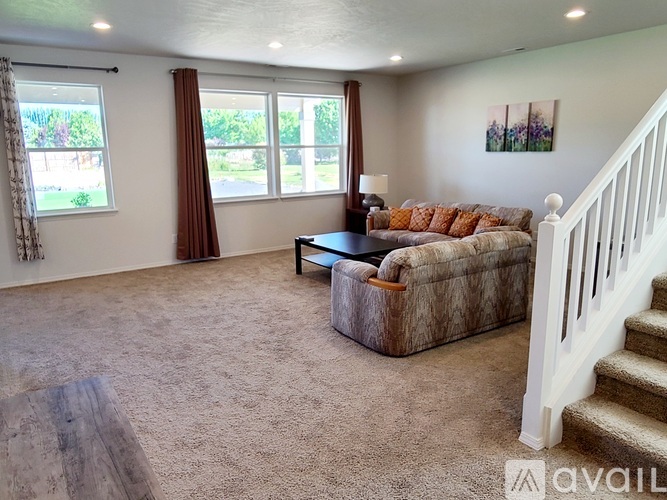 A living room with a couch, a coffee table, and a staircase.