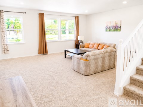 A living room with a couch, a coffee table, and a staircase.