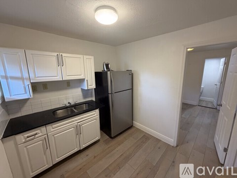 A kitchen with white cabinets and a black countertop.