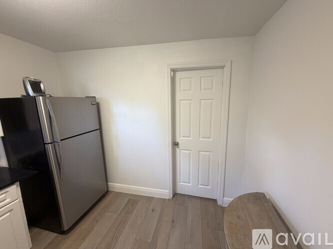 A kitchen with a black fridge and a white door.