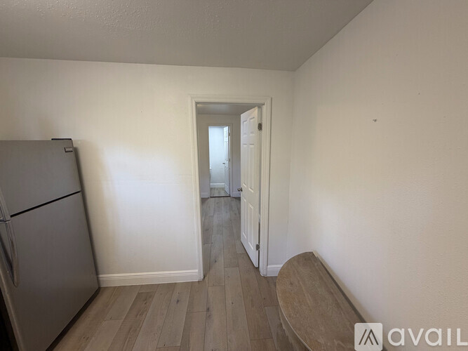 A kitchen with a refrigerator and a doorway leading to another room.