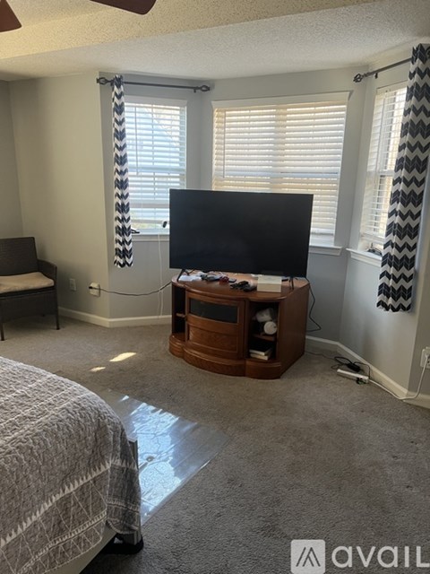 A bedroom with a bed, a television, and a window with blinds.