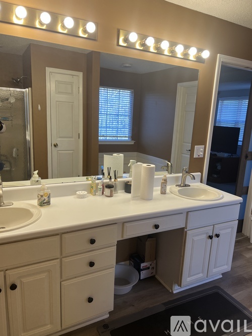 A bathroom with a vanity and a mirror with lights above it.